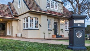 Een huis met twee verdiepingen, een beige gevel en een dak met rode tegels. Er is een zwarte brievenbus met het nummer 16 erop.