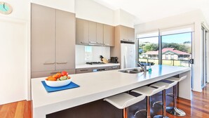 A modern kitchen with a large island, bar stools, and a view of the outdoors.