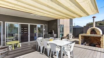 An outdoor patio with a table and chairs, a grill, and a pizza oven.