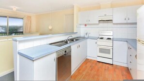 A modern kitchen with white cabinets, a dishwasher, a stove, and a sink. - Tahren Beachfront Shack Wifi - Pet-friendly (Middleton)