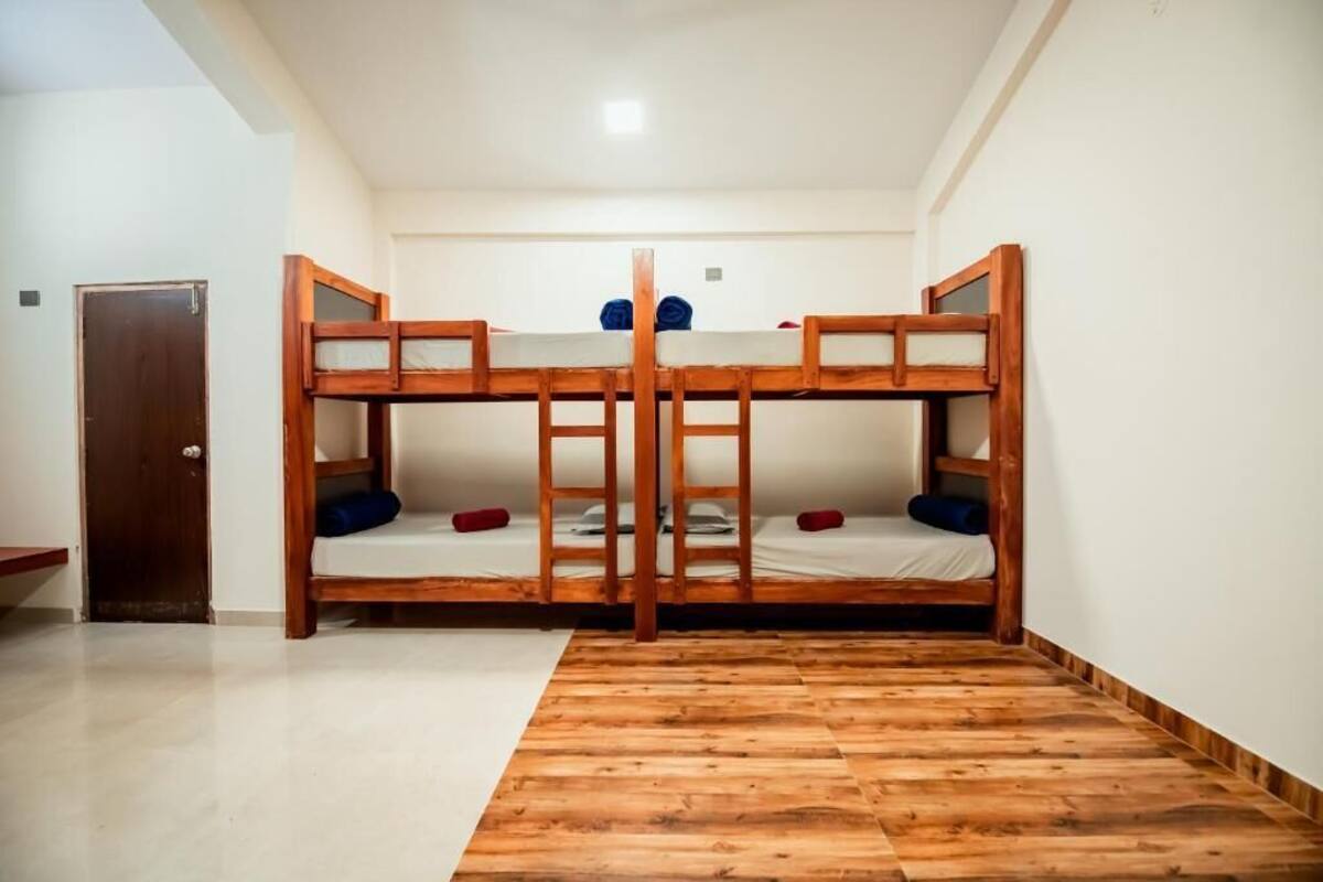 Una stanza con due letti a castello, un pavimento in legno e una porta.