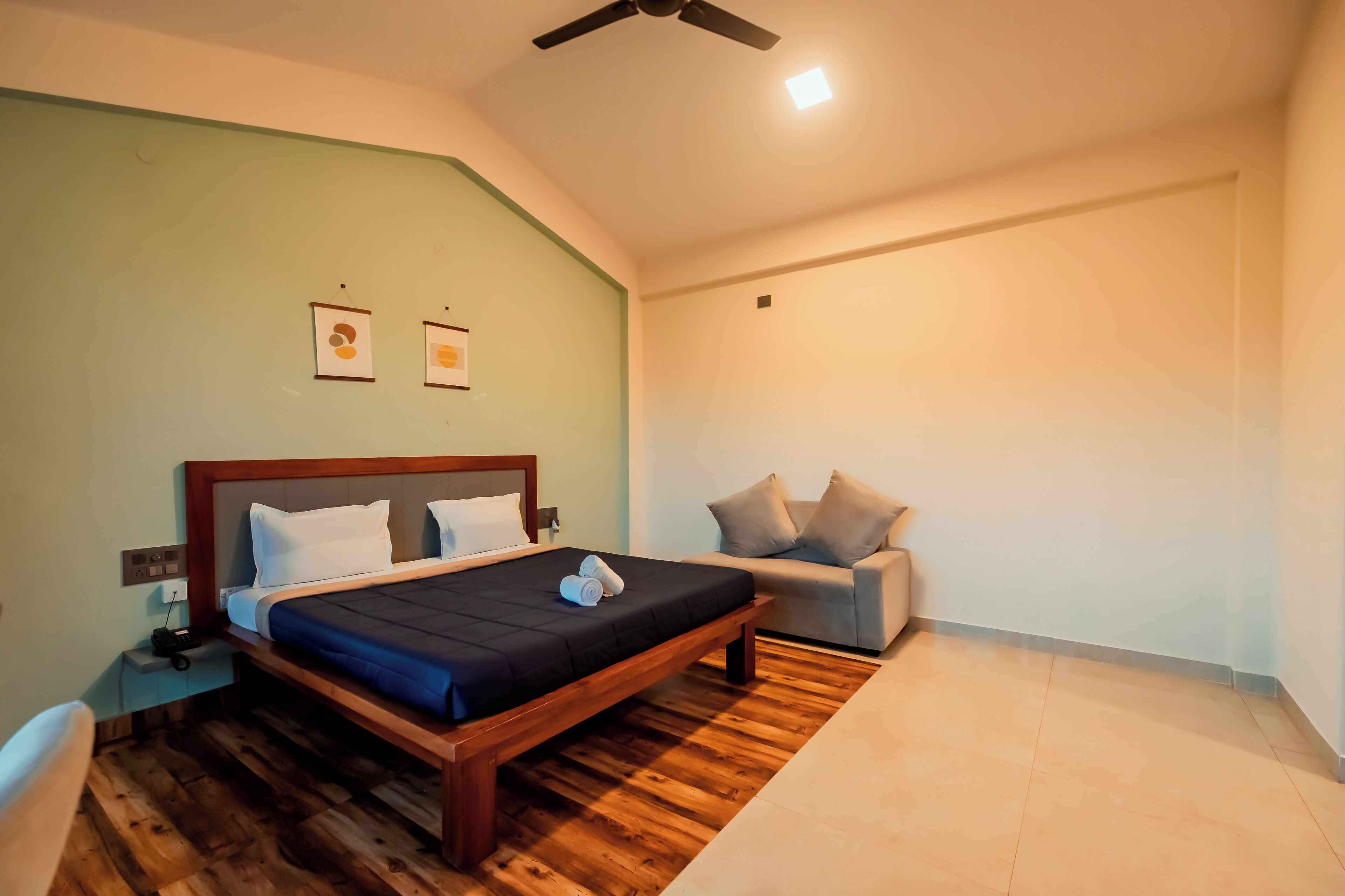 A bedroom with a bed, a nightstand, a sofa, and a ceiling fan.