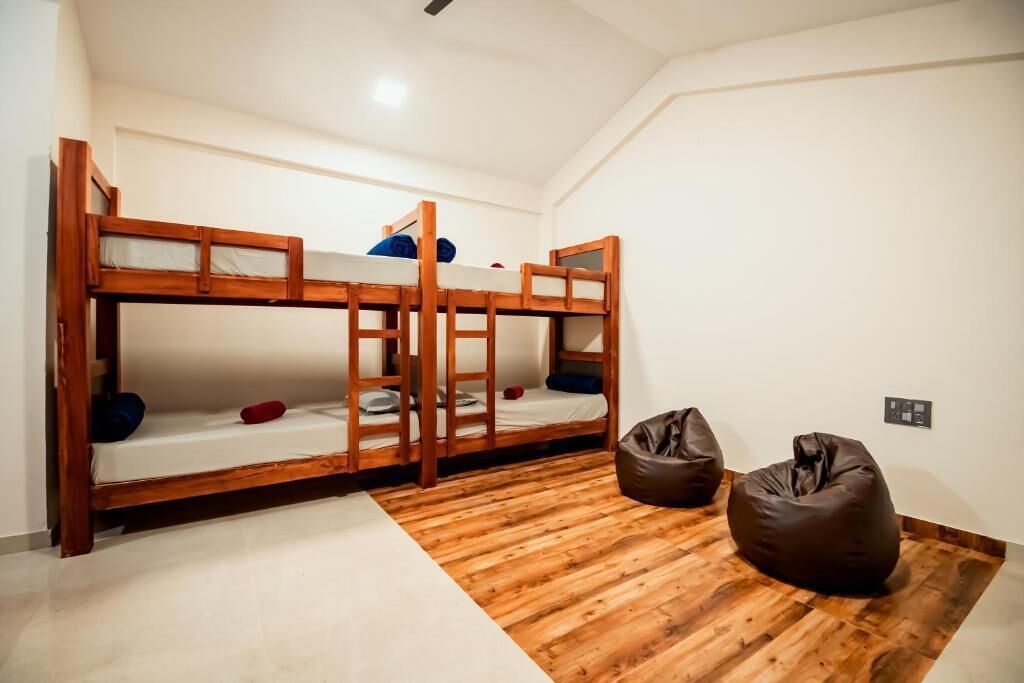A room with three bunk beds, a wooden floor, and two bean bags.
