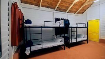 A dormitory room with bunk beds, a yellow door, and a wooden ceiling.