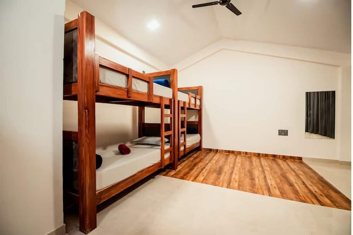 Una stanza con tre letti a castello in legno, una ventola a soffitto e una finestra con tende.