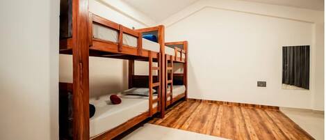 A room with three wooden bunk beds, a ceiling fan, and a window with curtains.