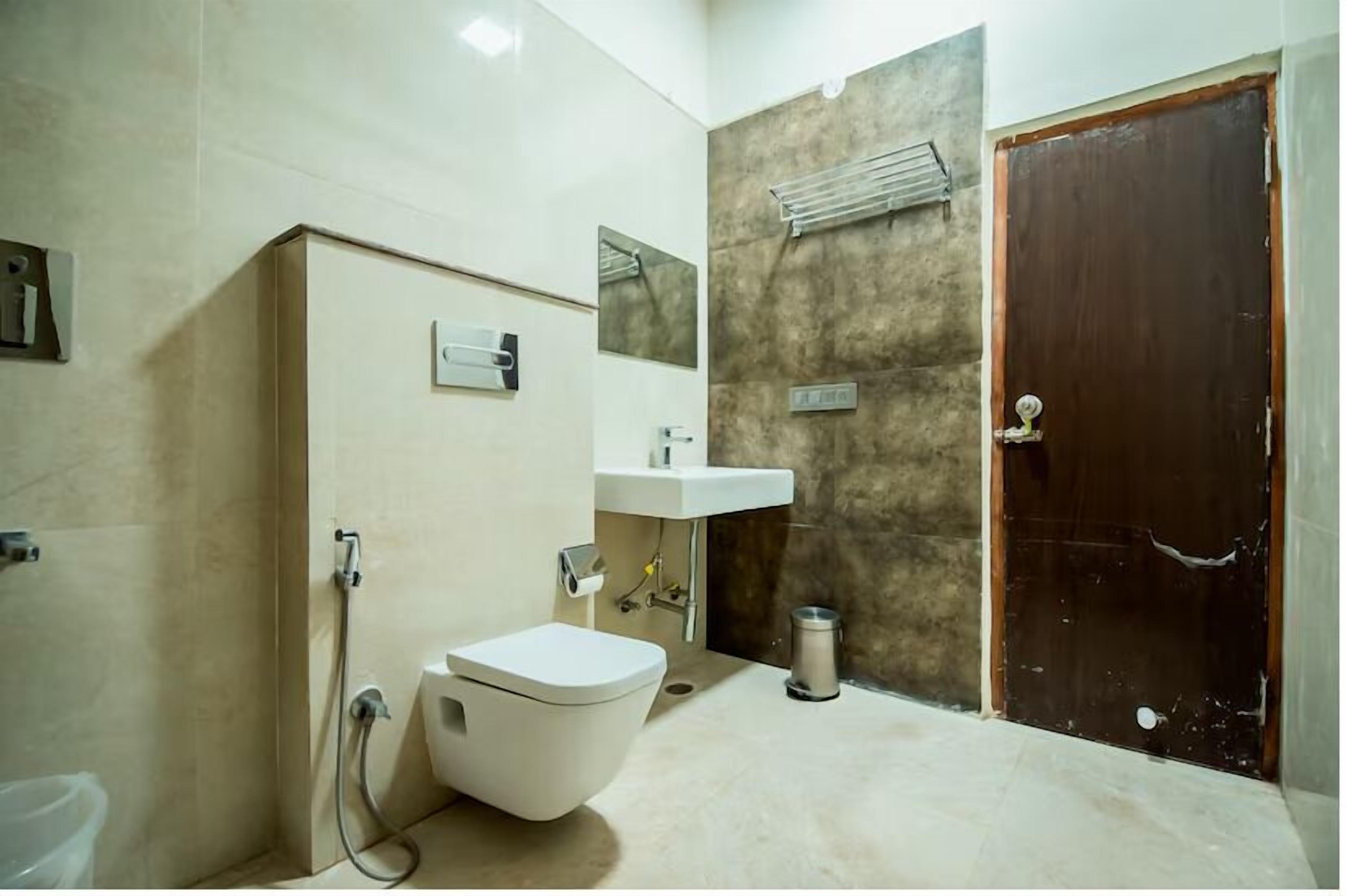 Une salle de bain comprenant des toilettes, un lavabo, une douche et une porte.