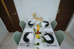 A dining area with a table set for four, featuring a centerpiece with lemons and dried flowers.