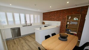 Una cocina moderna con armarios blancos, una mesa de comedor de madera y una pared de ladrillo decorativa.
