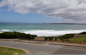 A coastal road with a view of the sea and distant hills. - Southern Sands Beachfront Apartment (Port Elliot)