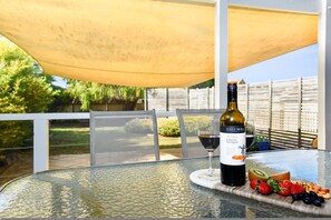 Un tavolo con una bottiglia di vino, un bicchiere di vino e un piatto di frutta.