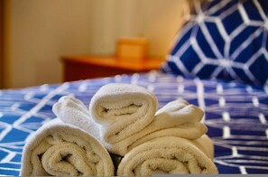 Un lit avec des serviettes blanches roulées et une couvre-lit bleue à motifs.