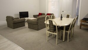 A living room with a TV, sofas, a dining table, and chairs.