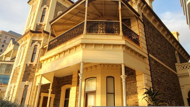 A historic building with a corner balcony, large windows, and a stone facade.