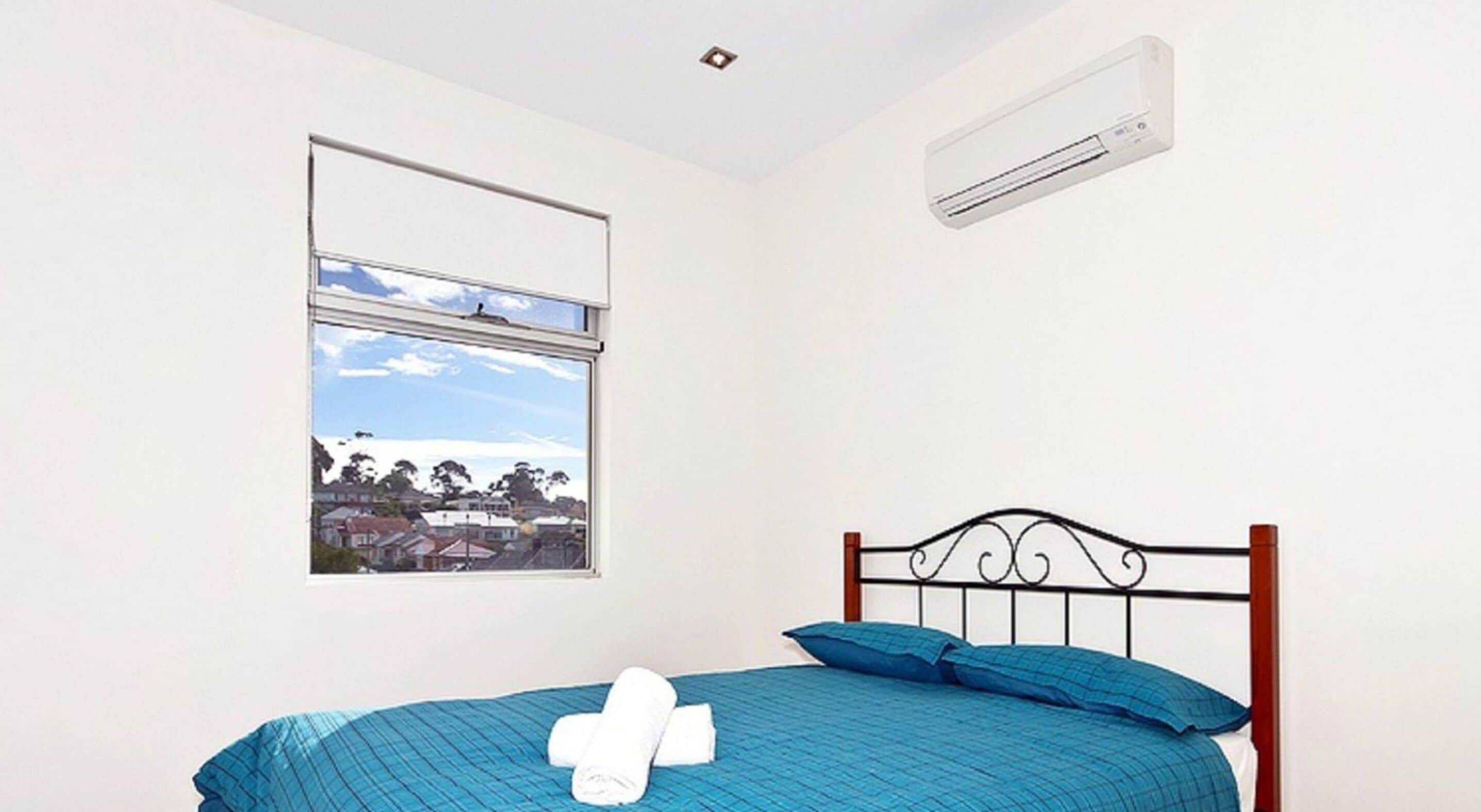 Een slaapkamer met een bed, een raam met uitzicht en een airconditioning.