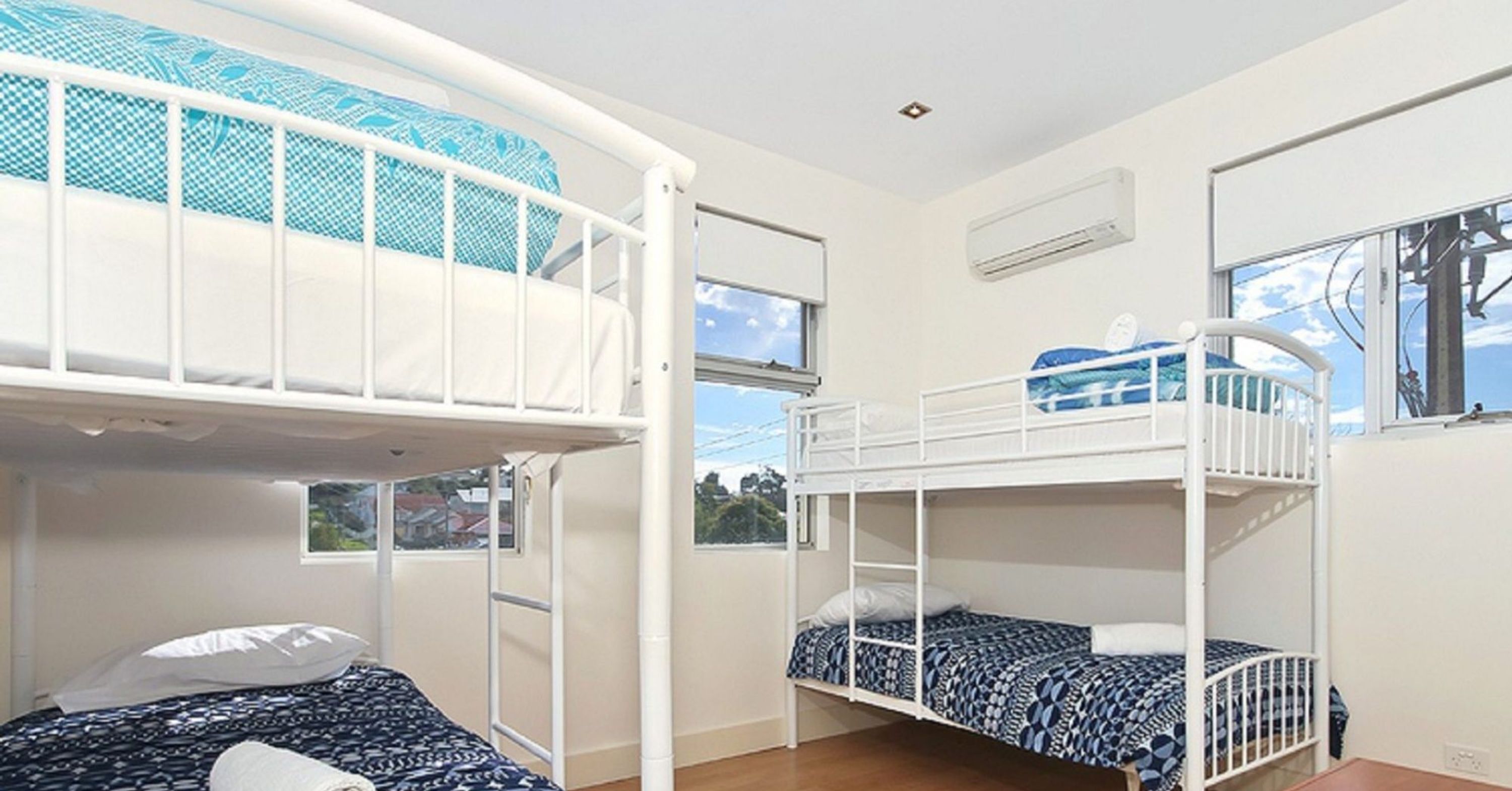 A room with bunk beds, a window, and an air conditioning unit.