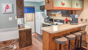 A compact kitchen with a refrigerator, microwave, stove, and bar stools. - The Red Chair Retreat at Red River (Red River)