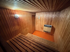Un sauna avec des murs en bois, un banc et un appareil de chauffage pour sauna.