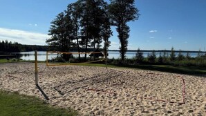Une plage de sable avec un filet de volley-ball et des arbres en arrière-plan.