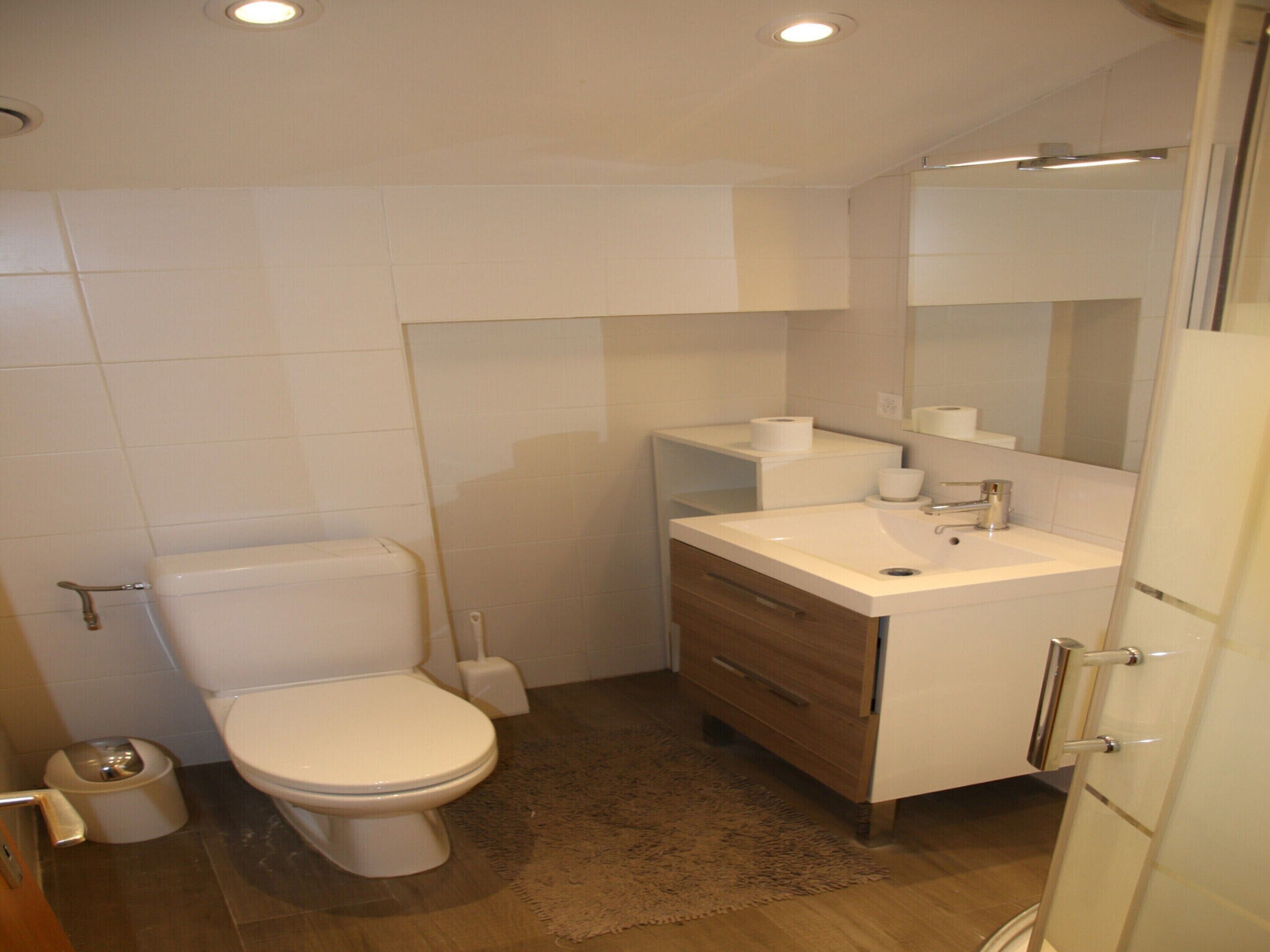 A modern bathroom with a toilet, sink, and mirror.