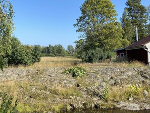 A rural landscape with a small red building, a rocky foreground, and a field in the background. - 4 Person Holiday Home in Animskog (Ånimskog)