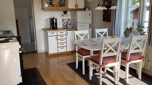 A compact kitchen with a dining area, featuring a refrigerator, stove, and a dining table with chairs. - 4 Person Holiday Home in Animskog (Ånimskog)