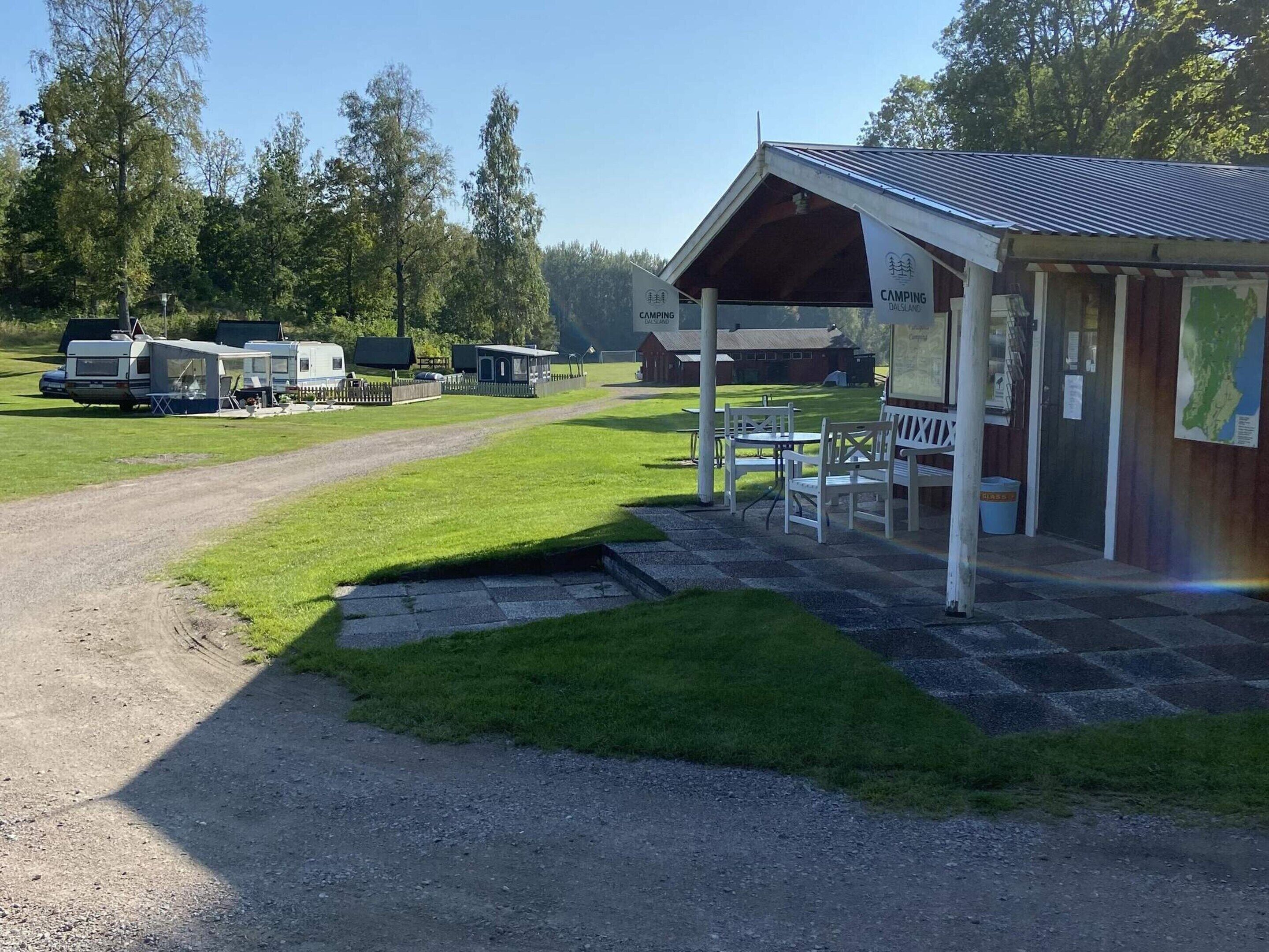 A campground with RVs, a covered picnic area, and a building with a sign.