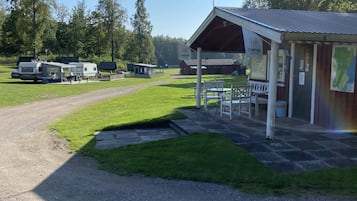 A campground with RVs, a covered picnic area, and a building with a sign.