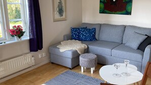 A living room with a grey sofa, a white coffee table, and a window with curtains. - 4 Person Holiday Home in Animskog (Ånimskog)