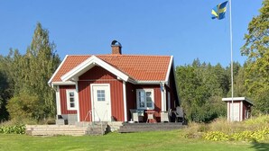 A red wooden house with a white door and windows, a chimney, and a flagpole with a flag. - 4 Person Holiday Home in Animskog (Ånimskog)