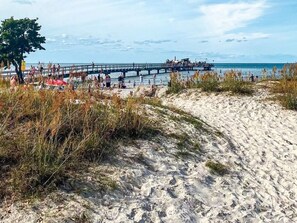 A beach with a pier extending into the water, sandy dunes, and a clear sky. - 4 Person Holiday Home in Kopingsvik (Kopingsvik)