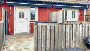 Un'area esterna in legno con un barbecue e un contenitore portaoggetti in metallo.