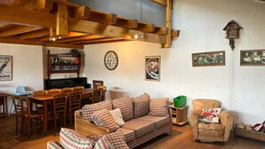 A cozy living room with a wooden ceiling, a plaid sofa, a wooden dining table, and a clock on the wall. - Chalet With Mesmerizing Mountain View (Veysonnaz)