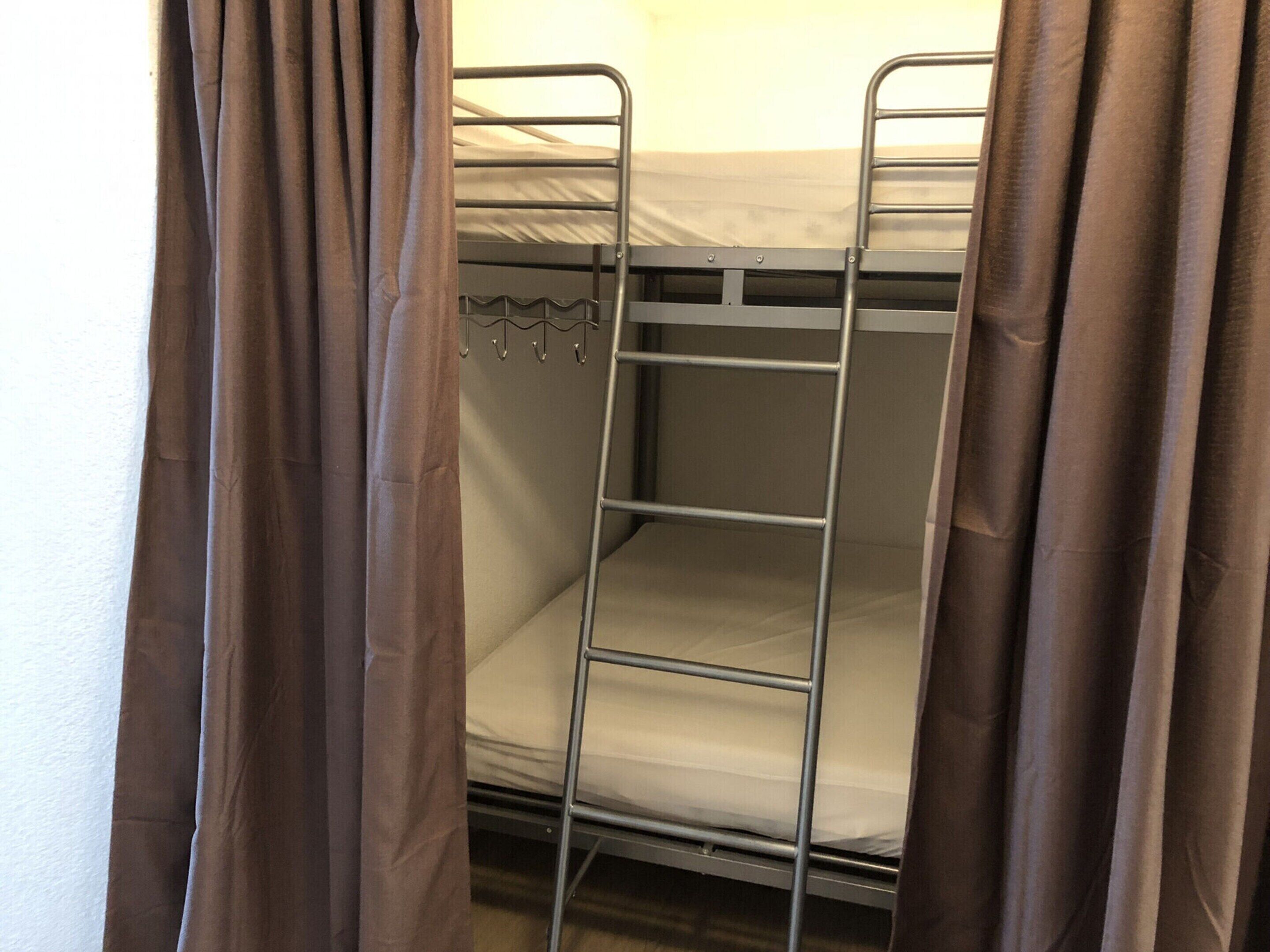 Un lit superposé avec des barreaux en métal et un matelas blanc.