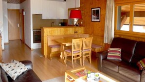 A cozy cabin interior with a wooden dining table, chairs, a sofa, and a coffee table. - Apartment for Relaxed Vacation (Veysonnaz)