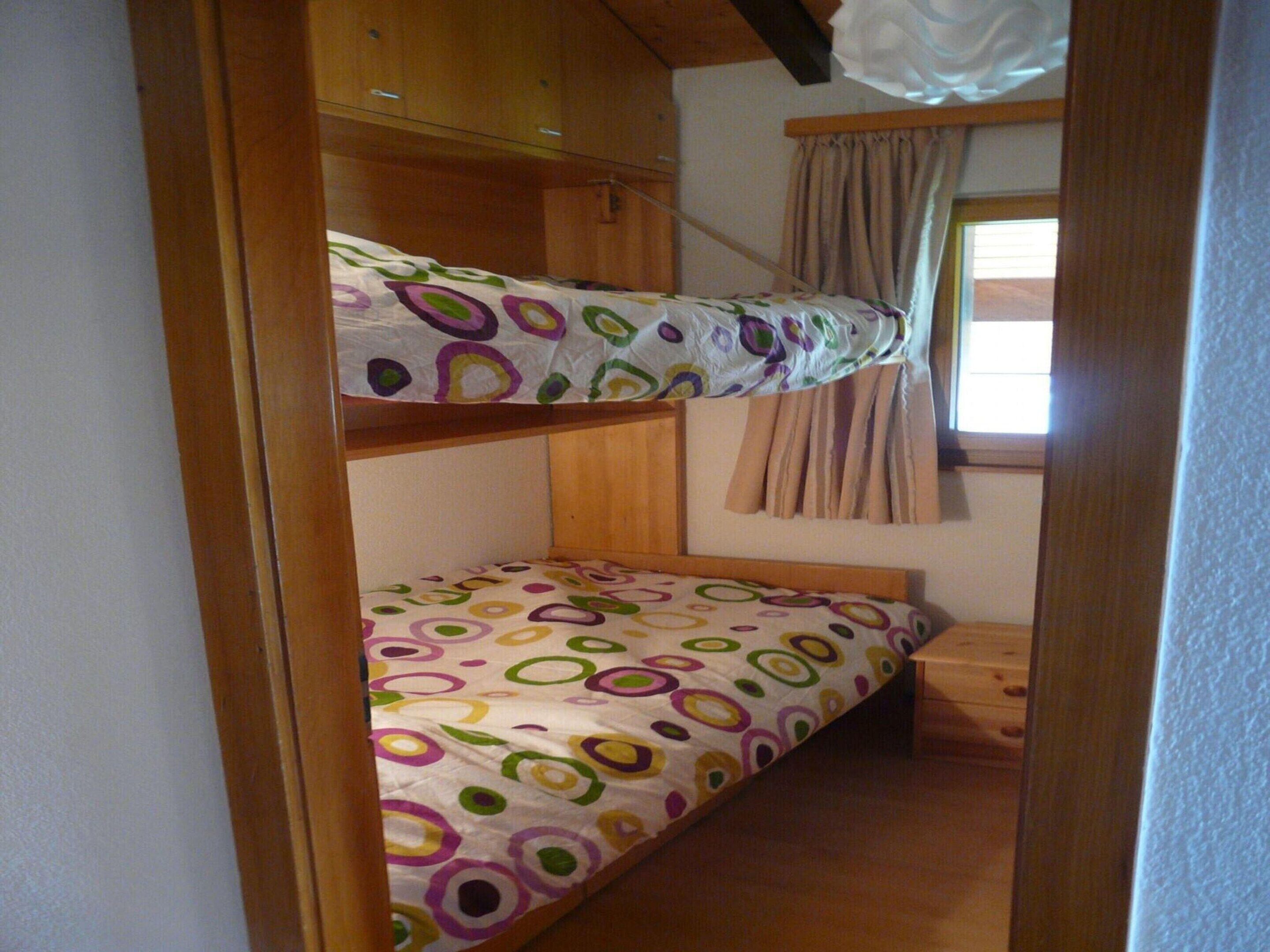 Une chambre avec un lit superposé, une fenêtre et des rideaux.