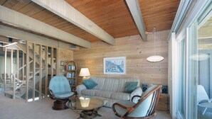 A cozy living room with a wooden ceiling, a sofa, two rocking chairs, a coffee table, and a bookshelf. - Charming 2 bedroom direct oceanfront townhouse in family friendly midtown. (Ocean City)