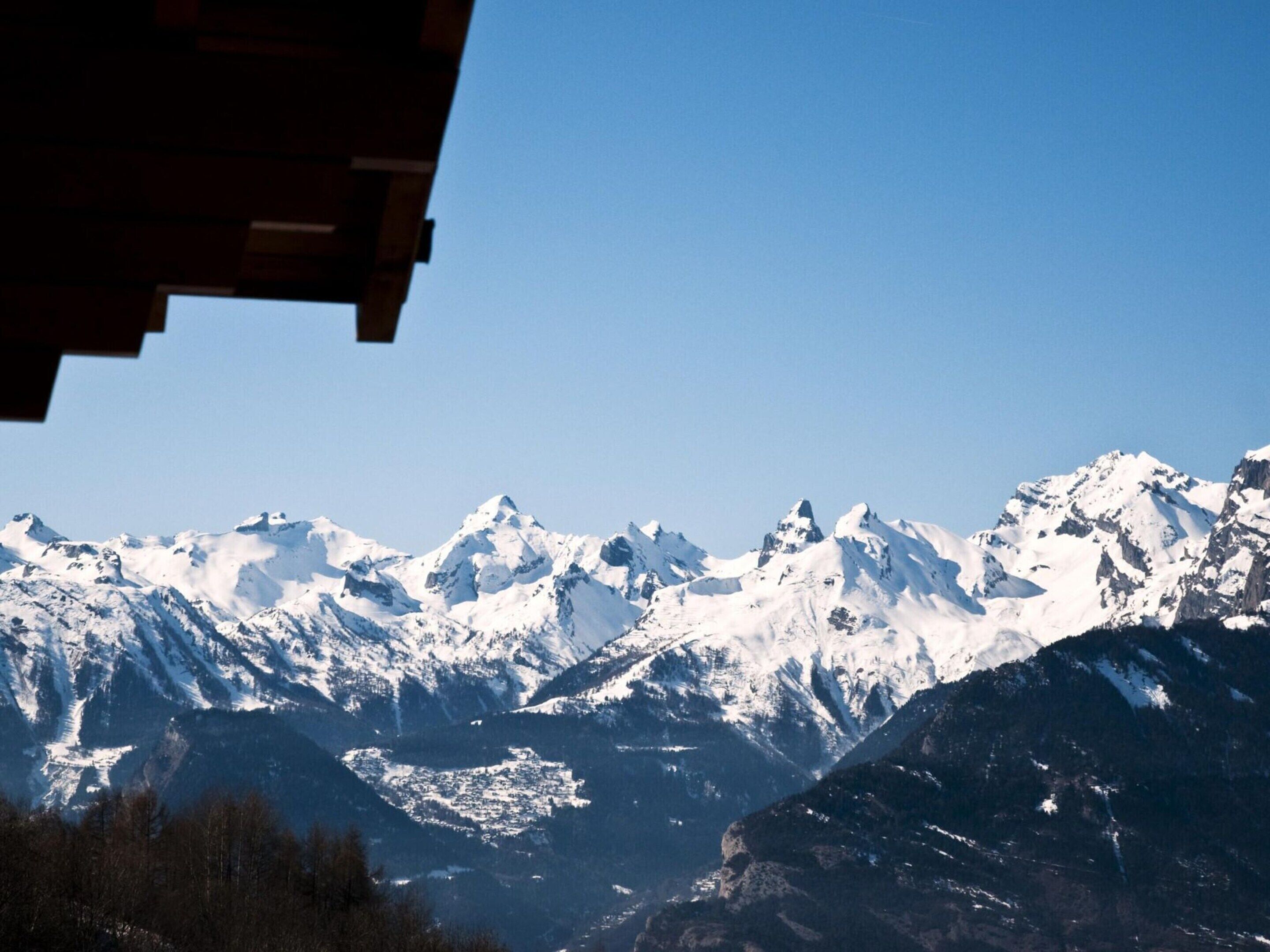A mountain range with snow-covered peaks and a clear sky.