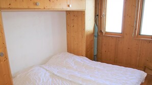 A single bed with a white duvet in a room with wooden walls and a window. - Cozy Apartment With Valley Views (Veysonnaz)