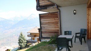 A patio with a table and chairs, overlooking a mountainous landscape. - Cozy Apartment With Valley Views (Veysonnaz)