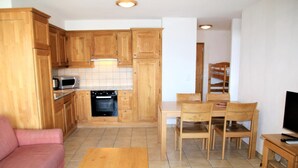 A compact living space with wooden cabinetry, a kitchenette, a dining area, and a seating area with a sofa and a coffee table. - Cozy Apartment With Valley Views (Veysonnaz)