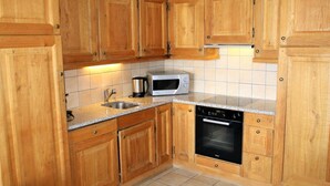 A kitchen with wooden cabinets, a microwave, a coffee maker, and a dishwasher. - Cozy Apartment With Valley Views (Veysonnaz)