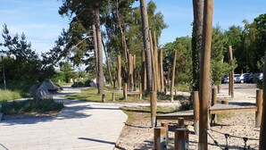 A paved walkway with wooden posts and benches, surrounded by trees and greenery.