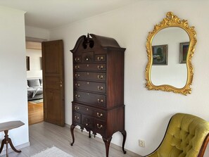 A room with a large wooden dresser, a mirror with an ornate frame, and a green upholstered chair. - 4 Star Holiday Home in Amal (Åmål)