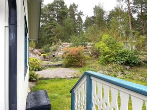 Una propiedad residencial con un sendero de piedra que conduce a una terraza de madera, rodeada de exuberante vegetación y árboles.