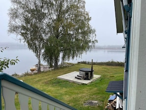 A view of a lake with a wooden deck and a fire pit, surrounded by trees and a grassy area. - 4 Star Holiday Home in Amal (Åmål)