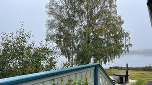 A view from a balcony overlooking a lake with a wooden deck and a gazebo.