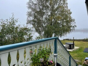 A view from a balcony overlooking a lake with a wooden deck and a gazebo.
