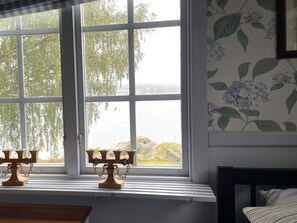 A room with a large window, a wooden candelabra on the sill, and a bed with a striped pillow. - 4 Star Holiday Home in Amal (Åmål)