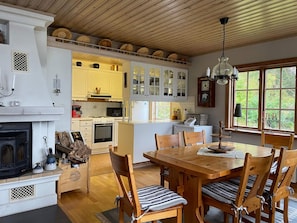 A cozy kitchen with a fireplace, wooden dining table, and chairs. - 4 Star Holiday Home in Amal (Åmål)
